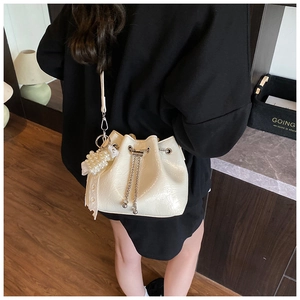 Detail of off-white pleated bucket bag with pearl heart charm and silver chain strap