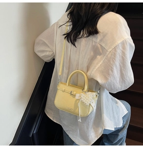 Petit sac seau en cuir souple jaune clair avec breloque cœur perlé porté par un mannequin