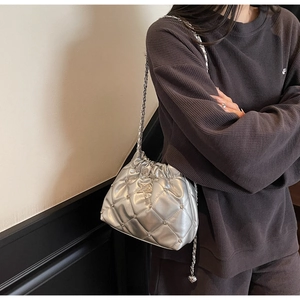 Détail d'un sac seau matelassé argenté avec insigne étoile et chaîne en métal