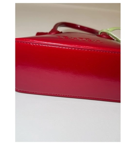 Detail of red glossy leather bucket bag showing fine stitching and embossed logo design