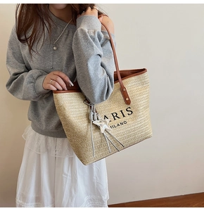 Detail of woven beach tote featuring Paris Milano text, leather trim, and star charm