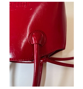 Detailed macro view of red glossy tote bag with embossed logo and reinforced stitching