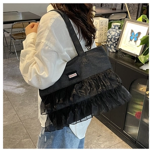 Detailed close-up of dark denim tote bag featuring multi-layered black organza lace ruffles