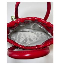 Detail view of red patent leather bucket bag featuring herringbone lining and magnetic clasp