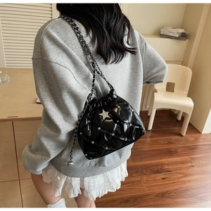Détail d'un sac seau matelassé noir avec clous étoiles et bandoulière chaîne argent