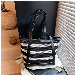 Detail of striped tote bag featuring mesh texture, black leather trim and long shoulder strap