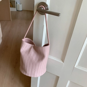 Detail shot of pink woven bucket bag with fine leather texture and slim shoulder strap