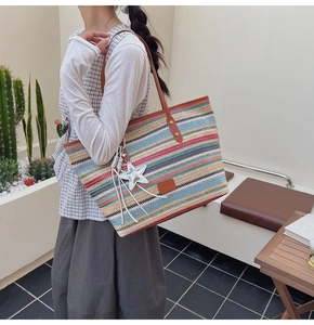 Detail of colorful rainbow woven tote bag with brown leather straps and star pendant