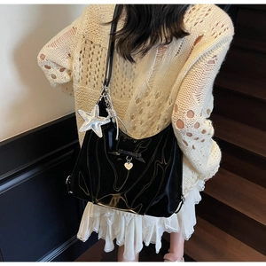 Detail of black patent leather hobo bag with star charm and heart pendant on shoulder