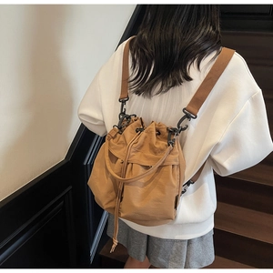 Detailed view of tan drawstring bucket bag with sturdy metallic carabiner and wide strap
