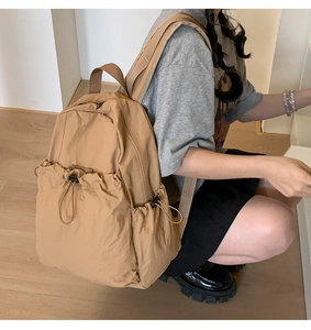 Detail of khaki drawstring backpack featuring nylon texture and side pocket construction