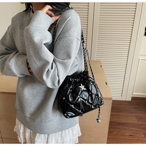 Détail du sac seau noir matelassé avec cristaux et pendentif étoile argenté sur chaîne
