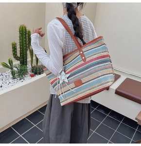 Detail of colorful rainbow woven straw tote bag with brown leather handles on shoulder