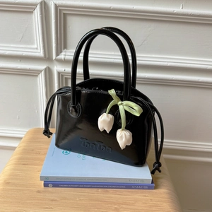Detail of black patent leather handbag with tulip flower charm and TonTon logo