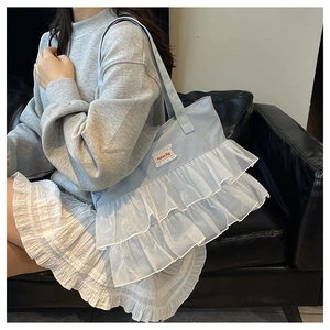 Detail of light blue denim tote bag with white tulle ruffles shown in a lifestyle setting