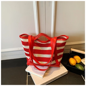 Detail of red and white striped knit tote bag resting on a book in a minimalist setting