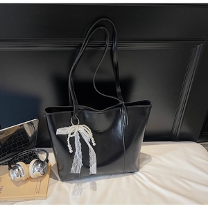 Detail of black PU leather tote bag with elegant pearl lace bow charm and text