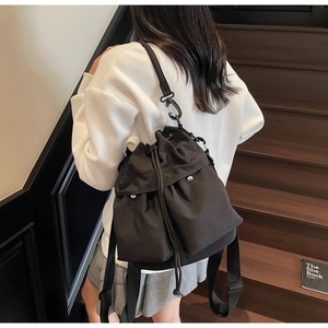 Rear view of a black drawstring bucket bag worn as a shoulder bag on stairs