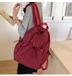 Side view of burgundy drawstring backpack with adjustable straps on a model back