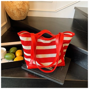 Detailed texture of red and white striped woven tote with premium red leather handles