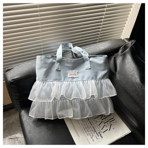 Detail of light blue denim tote bag with white tulle ruffles and Fashion Bag patch