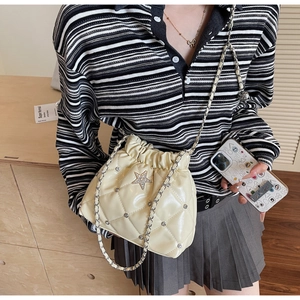 Détail du sac seau matelassé crème avec logo étoile en strass et bandoulière