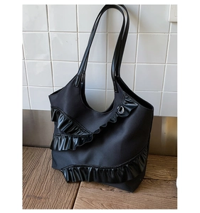 Detail of black lace ruffle texture and layered synthetic leather on the tote bag