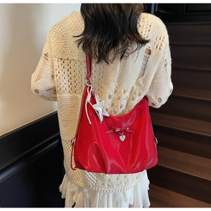 Detail of red glossy shoulder bag with bow and starfish pendant on a white outfit