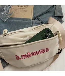 Détail du sac à bandoulière en cuir PU crème avec broderie rose et poche zippée interne