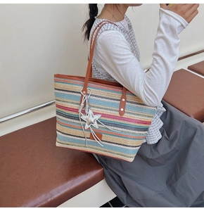 Detail view of colorful woven straw tote bag with brown leather handles and star charm