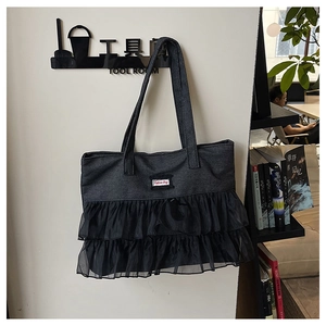 Detail of dark grey denim tote bag featuring double-layer black mesh pleats and logo patch