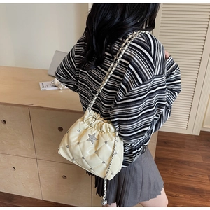 Sac seau matelassé crème avec breloques étoiles et bandoulière chaîne sur modèle
