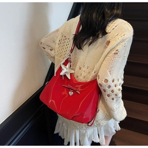 Detail of red patent leather shoulder bag with silver starfish and heart pendants