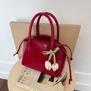 Detail of burgundy glossy bucket bag with floral charms and embossed lettering