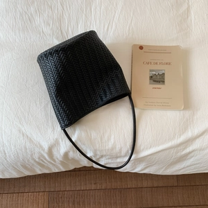 Close-up of black woven leather bucket bag with premium V-pattern texture and strap