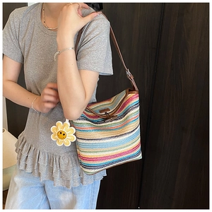 Detail of colorful striped woven bucket bag featuring wooden horn buckle and smiley charm