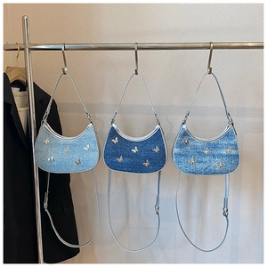 Tre borse a mezzaluna in denim blu chiaro, medio e scuro con farfalle in metallo
