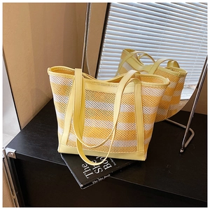 Close-up of yellow and white striped woven tote bag with leather straps and mesh texture