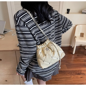Gros plan du sac seau matelassé crème avec logo étoile et détails en strass