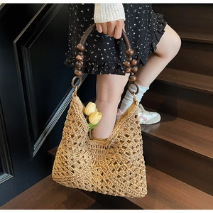 Detail of hollow woven tote bag with dark brown wooden beaded handle and floral accent