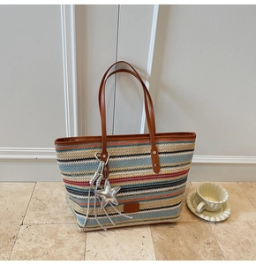 Detail of colorful striped woven tote bag featuring leather handles and star charm