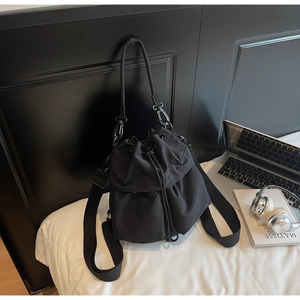 Detail of black drawstring bucket bag showing durable nylon material and metal hardware
