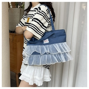Detail view of denim tote bag with white lace ruffle trim and Fashion Bag woven label