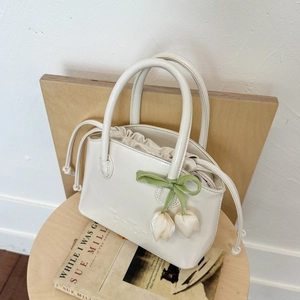 Detail of cream white leather bucket bag with pleated drawstring and tulip charm detail