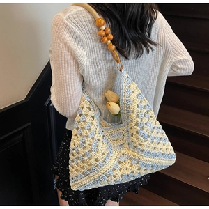Detail of hand-woven crochet tote bag with light blue patterns and wooden bead straps