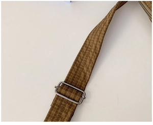 Details des verstellbaren braun karierten Nylon-Schultergurts mit Metallschnalle