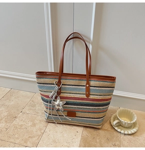 Detail of colorful woven tote bag with brown leather handles and a silver star charm