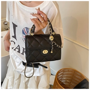 Detailed close-up of black quilted leather texture and gold metal chain strap with sphere charm