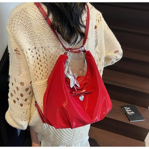 Rear view of a red patent leather hobo bag with star charm and heart tag on a model