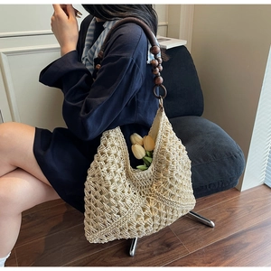 Detail of hand-woven cream tote with hollow texture and vintage dark wood bead handle